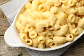 Delicious pasta with cheese sauce in baking dish on wooden table, top view