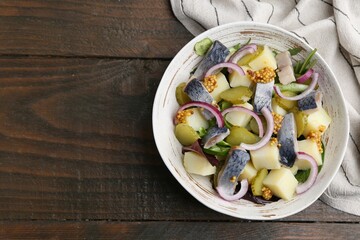 Delicious salad with herring, vegetables and mustard in bowl on wooden table, top view. Space for...