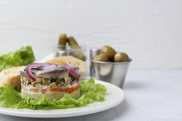 Delicious salad with herring and vegetables served on white tiled table, closeup. Space for text