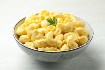 Delicious pasta with cheese sauce in bowl on light table, closeup