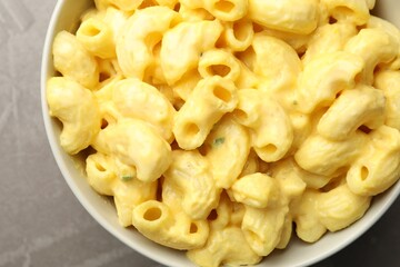 Delicious pasta with cheese sauce in bowl on grey table, top view