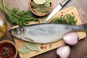 Salted herring, spices and knife on wooden table, flat lay