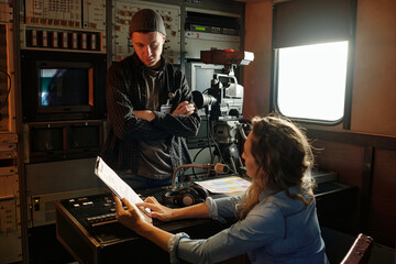 Young woman pointing at working document with text while consulting with male operator by sound...