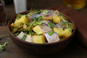 Delicious salad with herring on wooden table, closeup
