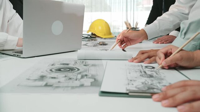Team members collaborate on engineering projects, analyzing blueprints and discussing technical details. The workspace includes laptops, safety gear, and drafting tools for effective planning. SACTR