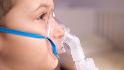 Caucasian boy inhales mist from a nebulizer for respiratory therapy, promoting recovery and wellness