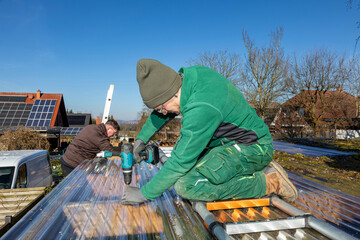 Team of Gardeners Installing Transparent Roof Panels with Power Tools.