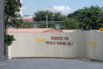 A photo of the entrance to a parking area with the message 'Reserved for private parking only' flanked by arrows pointing left and right, with a camera above, set against a suburban background