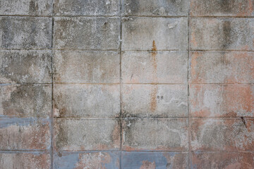 A dirty, dilapidated stone wall divided into rectangles, with rust-brown tints