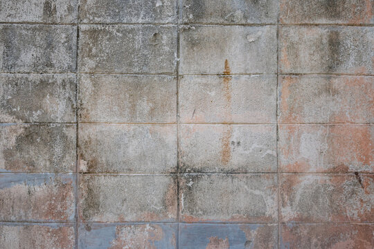 A dirty, dilapidated stone wall divided into rectangles, with rust-brown tints