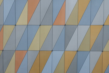 A straight-on view of an abstract wall with panels divided by slanted lines in pastel earth tones and gray