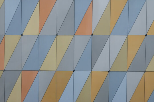 A straight-on view of an abstract wall with panels divided by slanted lines in pastel earth tones and gray
