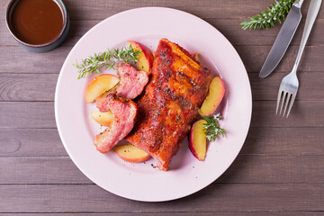 Barbecue grilled pork ribs with apples and rosemary on a plate. View from above, top view