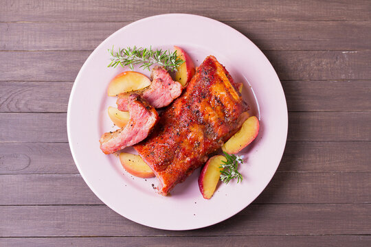 Barbecue grilled pork ribs with apples and rosemary on a plate. View from above, top view