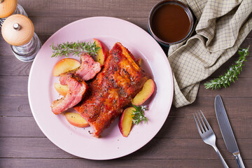 Barbecue grilled pork ribs with apples and rosemary on a plate. View from above, top view