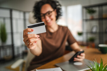 curly hair businesswoman buy online on cellphone with credit card at home