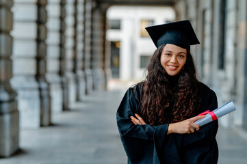 Confident and proud latin graduate smiling and holding her diploma in university cloister after...