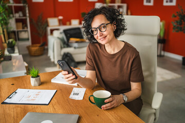mature woman work from home and use mobile phone on coffee break