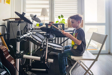 Boy playing drums at home. Learning music, development, knowledge, passion. Seven-year-old boy.