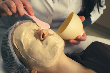 Alginate mask on woman face in beauty salon. Woman relaxing with anti aging mask. Cosmetologist putting alginate mask with spatula on face. Wellness procedure. Skincare treatment. Healthcare pleasure.