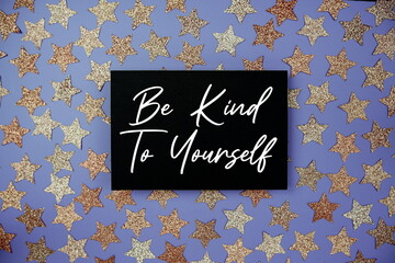 Be Kind To Yourself text  motivational and inspiration quote on paper card with star glitter decoration flat lay on purple background