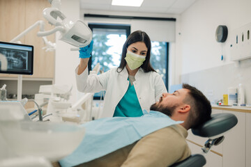 Dentist positioning dental x ray equipment over patient in clinic