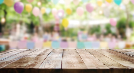 Empty wooden table for product placement, with a blurred outdoor children's party in the background, decorated with colorful balloons and banners.