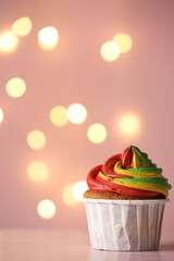 Delicious cupcake with colorful cream on table against pink background, closeup and space for text. Bokeh effect
