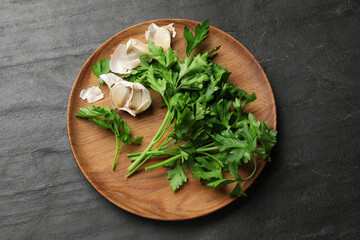 Fresh parsley and garlic on black table, top view