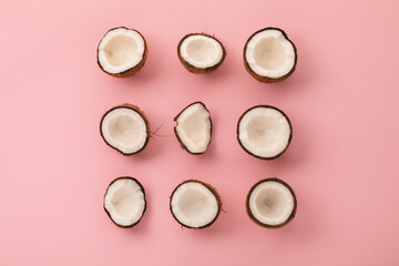 Pieces of cracked coconuts on pink background, flat lay