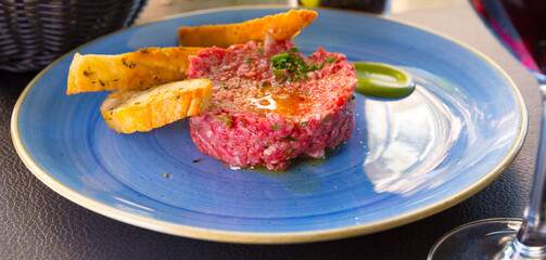 Image of delicious veal steak tartar served at plate with fried bread, food on cafe