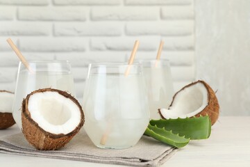 Refreshing drink with coconut and aloe on white table