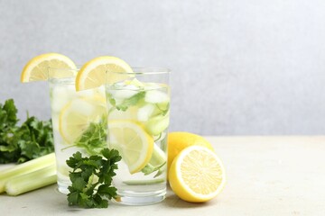 Healthy drink with parsley, lemons and celery on light grey table, space for text