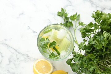 Healthy drink with parsley, cucumber, celery and lemons on white marble table, flat lay. Space for...