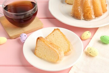Pieces of delicious bundt cake, Easter eggs and tea on pink wooden table, closeup