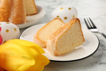 Pieces of delicious bundt cake, Easter eggs and tulip on light marble table, closeup