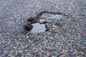 Asphalt pothole filled with rainwater.