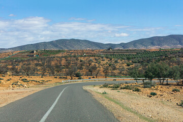 Winding asphalt road through the Atlas Mountains in Morocco. Serpentine route with road signs and...