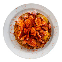 Chopped spicy boiled octopus tentacles with potato slices traditionally seasoned with aromatic smoked paprika. Isolated over white background