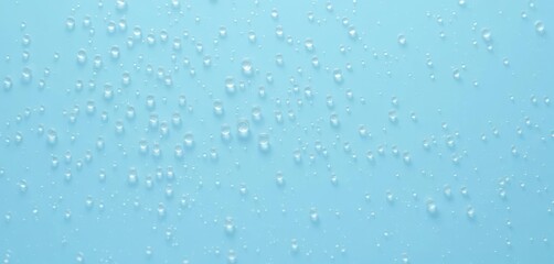 Tiny water droplets cling to a smooth, light blue surface, reflecting light, liquid, aqua, calm