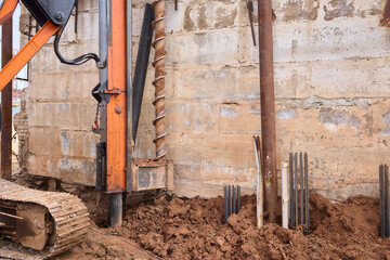 The excavator is actively working at the construction site on the foundation wall, making progress