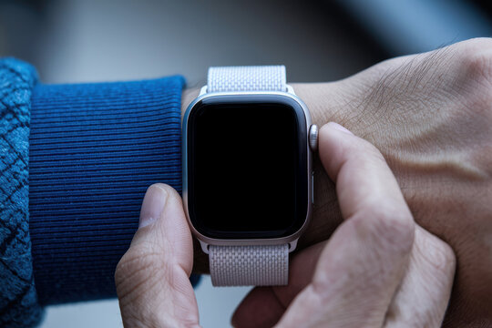 Detailed view of a man adjusting a smartwatch with a fabric sport band on his wrist, modern technology with a blank screen - Powered by Adobe