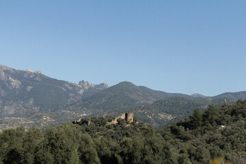 A historic fortress perched atop a hill in Turkey, surrounded by dense forests and majestic mountains.
