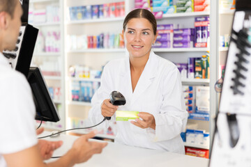 Obraz premium Man customer in pharmacy cash register area communicates with girl pharmacist, buys medicines, and receives advice. Customer in pharmacy near cash register is talking to pharmacist