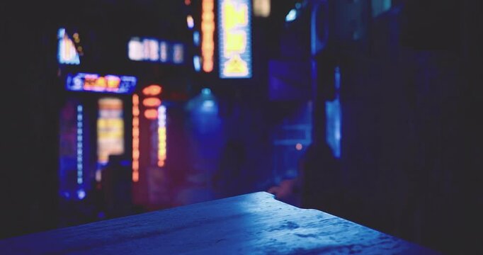 Colorful neon signs glow against the backdrop of a dark alley, creating a striking contrast. The atmosphere feels lively yet serene, showcasing city life after dusk.