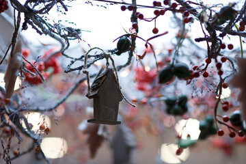 Delicate decorations featuring a wooden birdhouse and vibrant berries create a festive atmosphere in a cozy indoor space during the holiday season