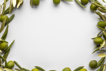 Minimalistic frame made of fresh green olives and branches on a white background