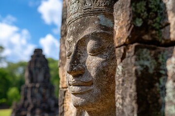 Obraz premium This stunning image showcases a stone figure with an intriguing expression, set against a backdrop of fluffy clouds, illustrating the blend of art and nature's beauty.