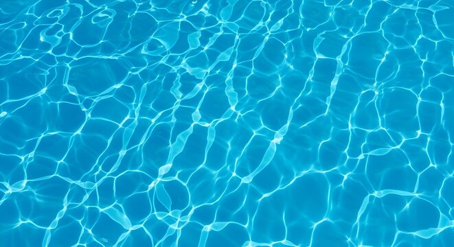 A top-down shot showing a close-up texture of clear blue water in a swimming pool or similar body of water. The sunlight creates a pattern of light and shadow on the water's surface.