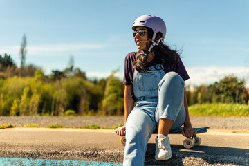 Latin skater girl relaxing and enjoying the sun sitting on her surfskate in pump track © EDER